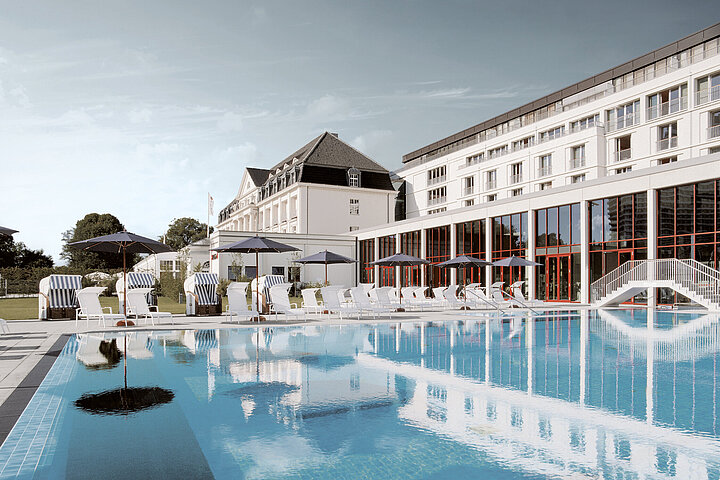 DSR_Asset_Projektentwicklung Outdoorpool am Hotel mit weißer Fassade, bewölkter Himmel